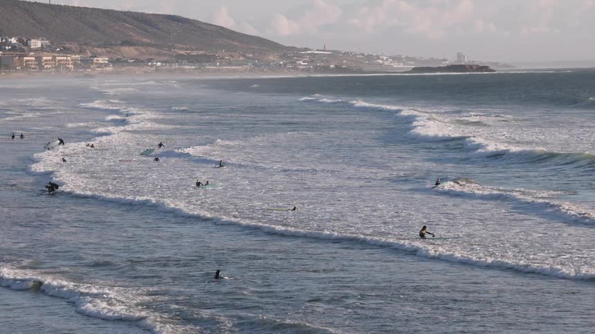Buildings along the coast as people swim in the water at the beach