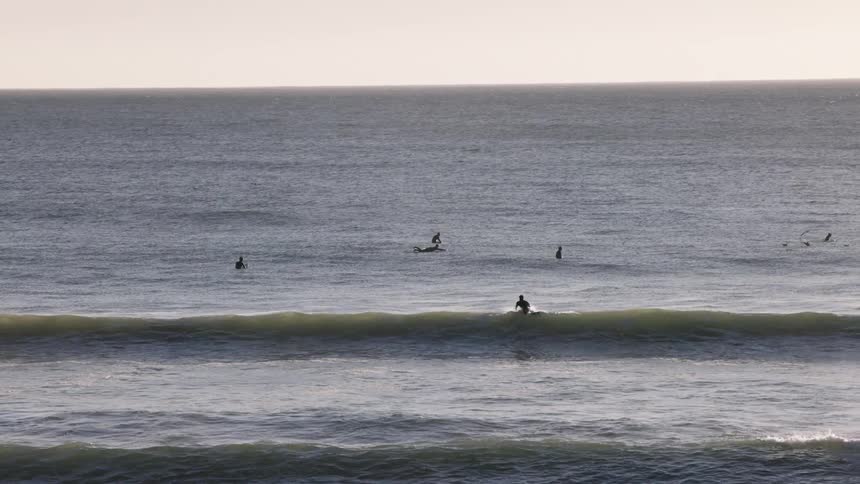 Surfers in a calm ocean at dawn