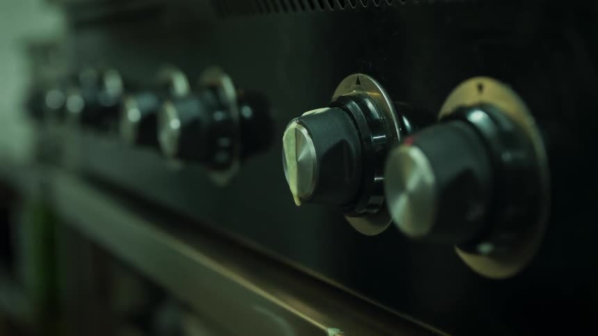 Stove knobs line the area between a row of vents and the oven door
