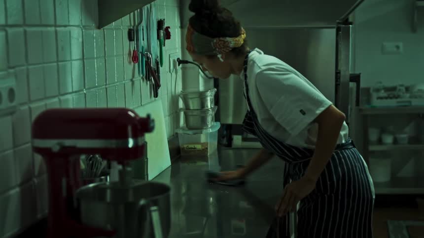 Woman cleaning a table in a restaurant kitchen