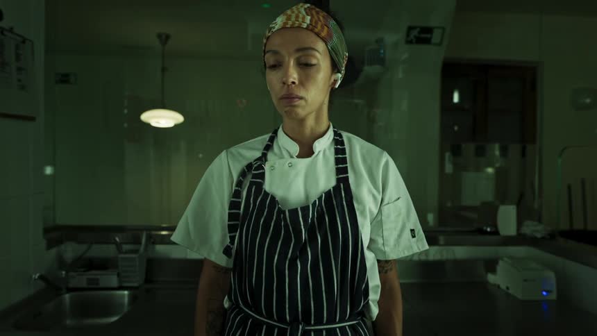 The woman is standing still in the kitchen