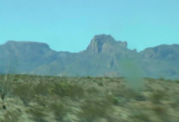 A view of a mountain in a landscape with a desert in front and low vegetation