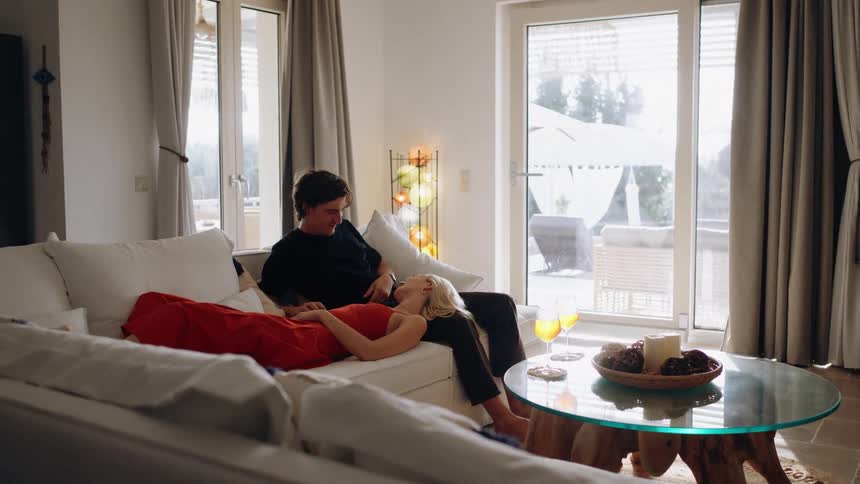 The woman lays on the mans lap on the couch