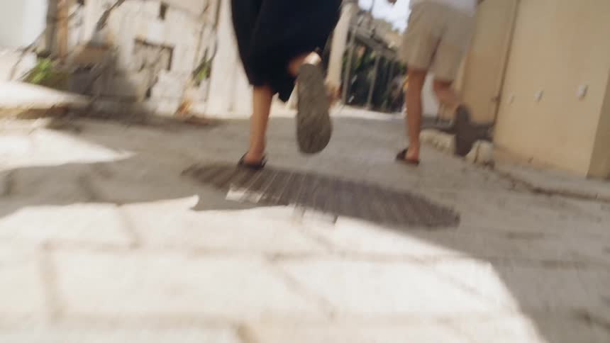 Man and woman running in an alley between apartment buildings