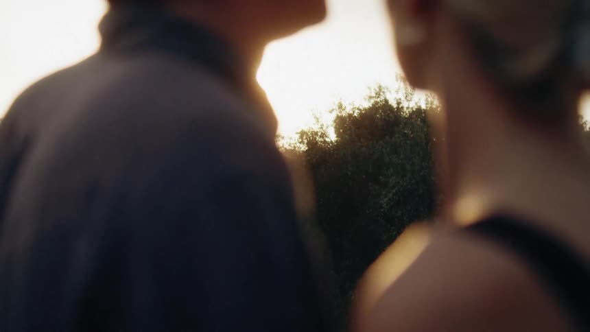 Man and woman standing outside together and he kisses her forehead