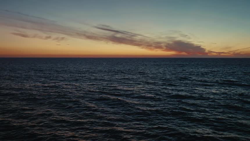 Ocean horizon at dusk with an orange sky and darktoned sea