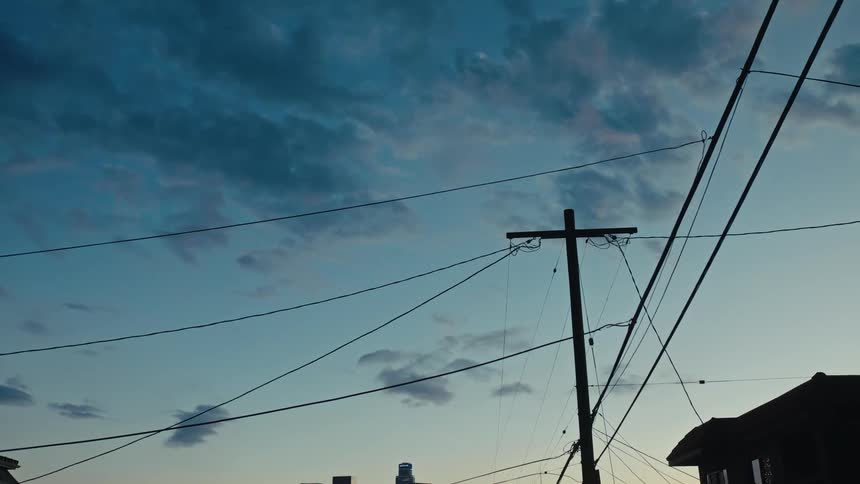 Utility pole and cables stretching across a neighborhood sky