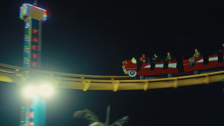 People riding a roller coaster as it moves around a curve at an amusement park