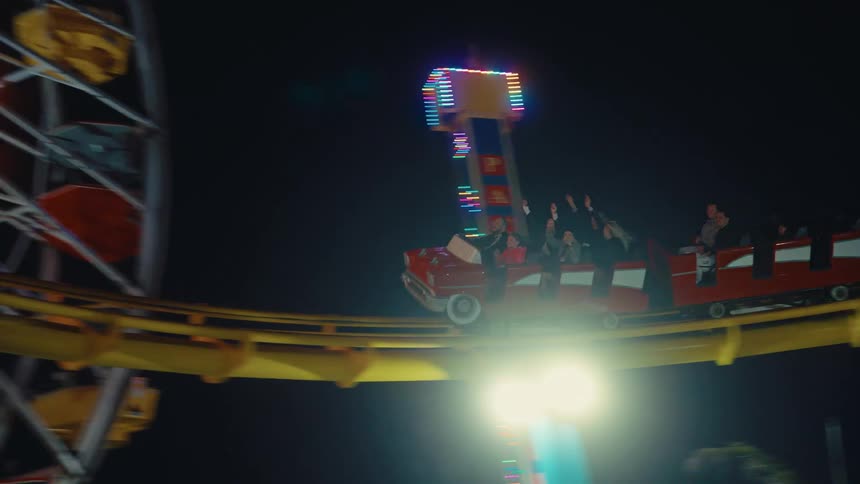 People riding a roller coaster as it moves around a curve at an amusement park