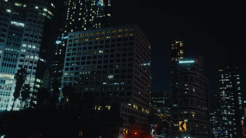 Vehicle travels through downtown at night with other traffic