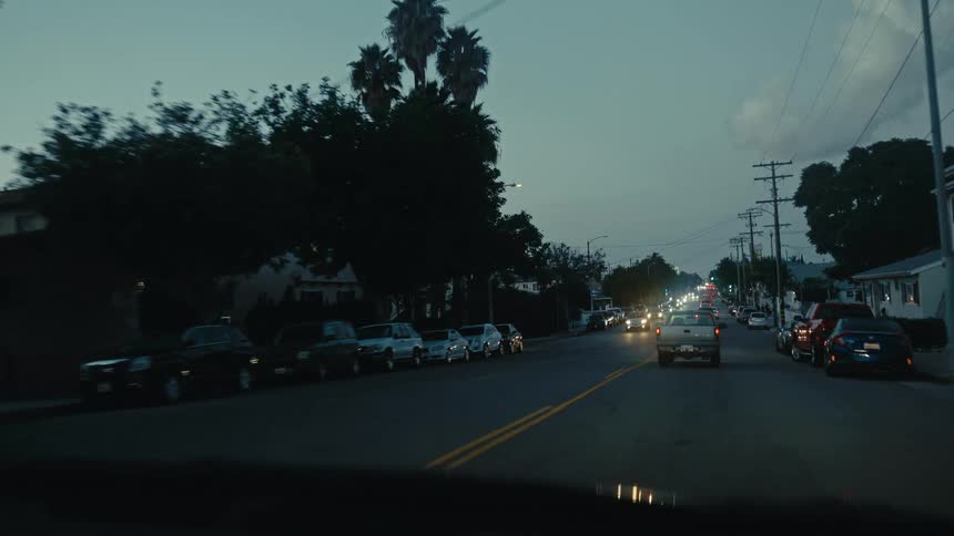 Cars drive on the road in town at sunset
