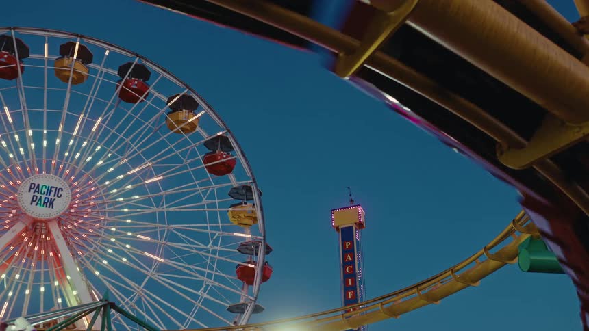 A roller coaster passes by with people in it at an amusement park