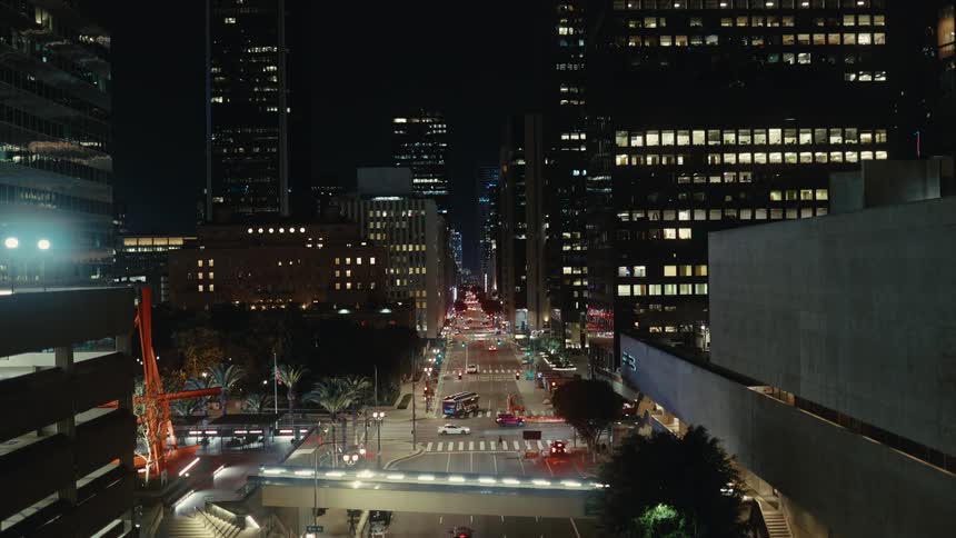 A city at night is shown with cars driving and building lights lit up