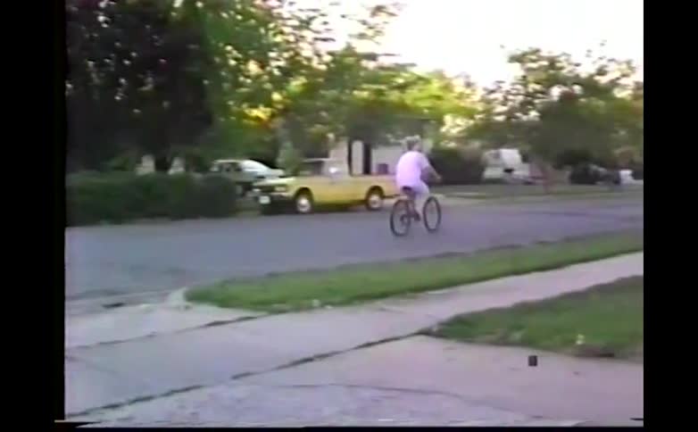 A woman rides a bicycle on a residential street on a summer day