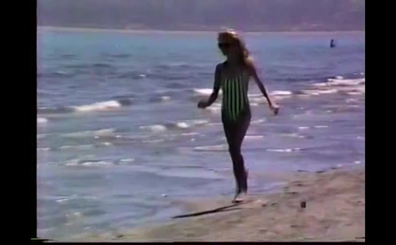 Young woman running across the beach as waves roll in to shore