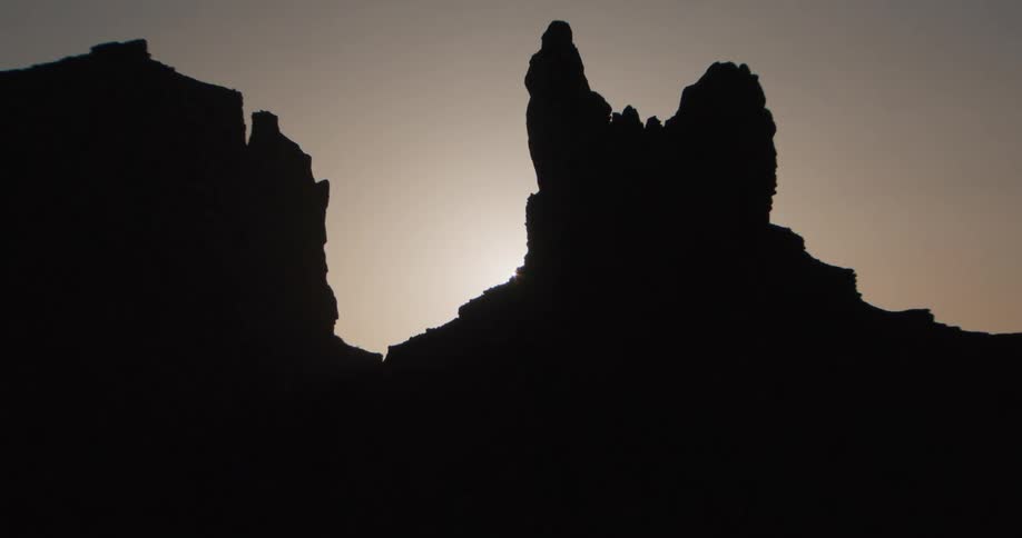 Sunlight near the horizon backlights cliffs and rock formations casting them into silhouette