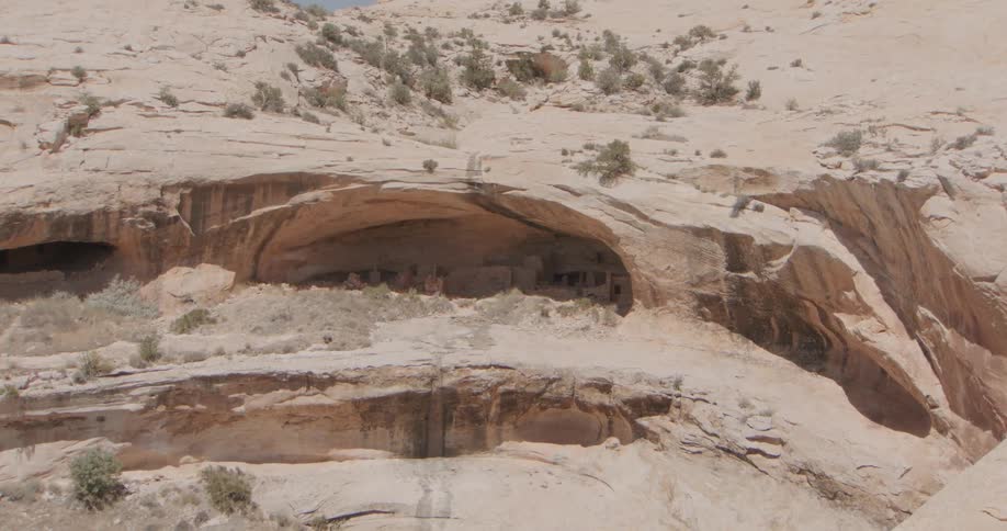 A dark cave sits on the side of a dry dusty mountain