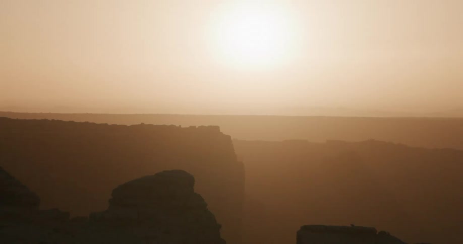 Low sun on the horizon illuminating layered rock formations with atmospheric haze