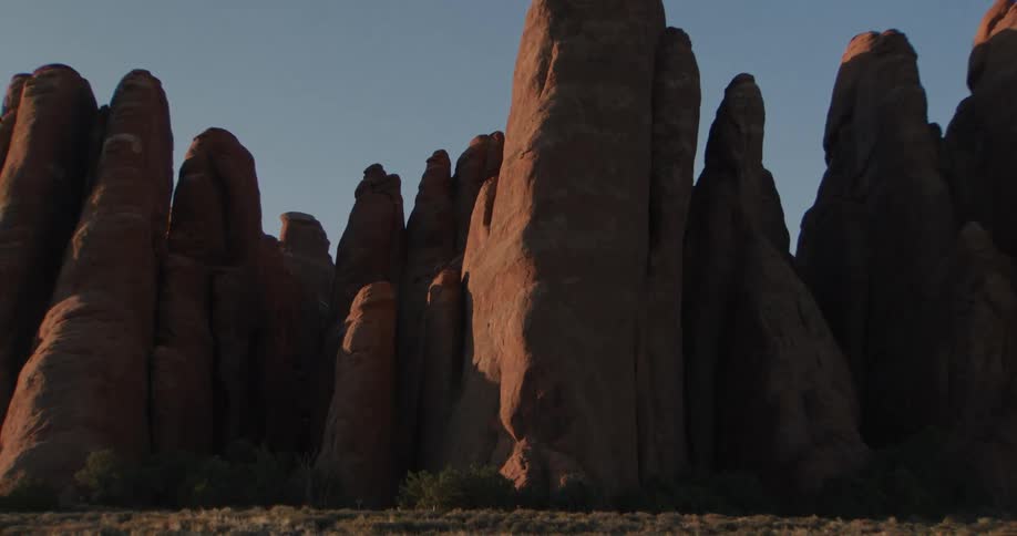 Cluster of natural stone column like formations tower over arid plains during the daytime