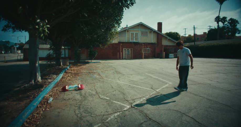A teenage boy slamming a skateboard onto a driveway at midday