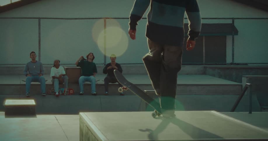 Teenager performs a skateboard stunt as his friends sit on their skateboards and watch