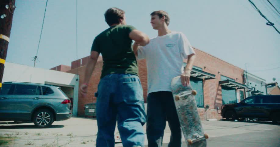 One skateboarder helps another get up off the street following an accident