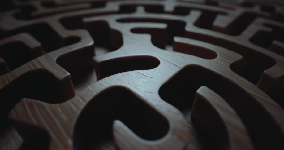 A dark intricately carved wooden maze with a single light source casting dramatic shadows