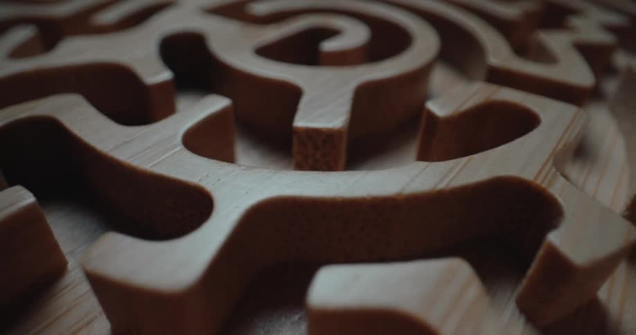 A close view of a carved wooden maze with intricate circular paths and smooth grain textures under soft light