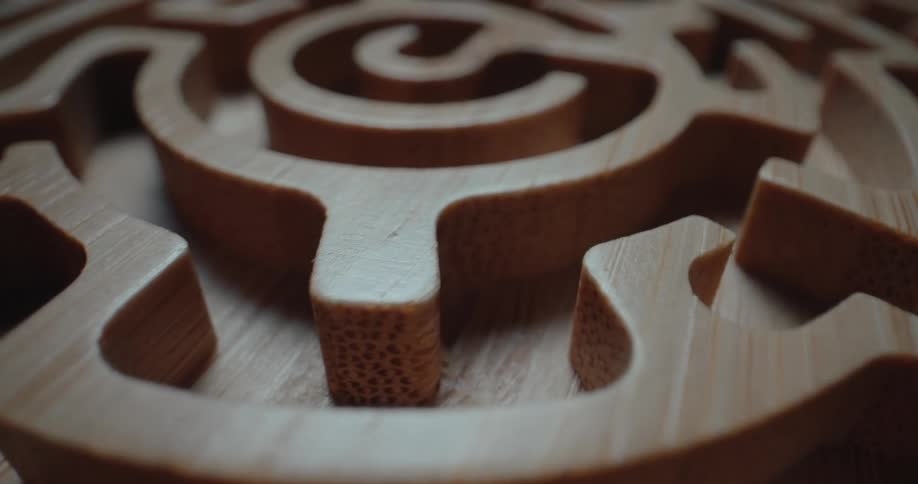 A close view of a carved wooden maze with intricate circular paths and smooth grain textures under soft light
