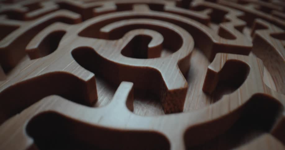 A small circular piece of wood has a maze carved into it