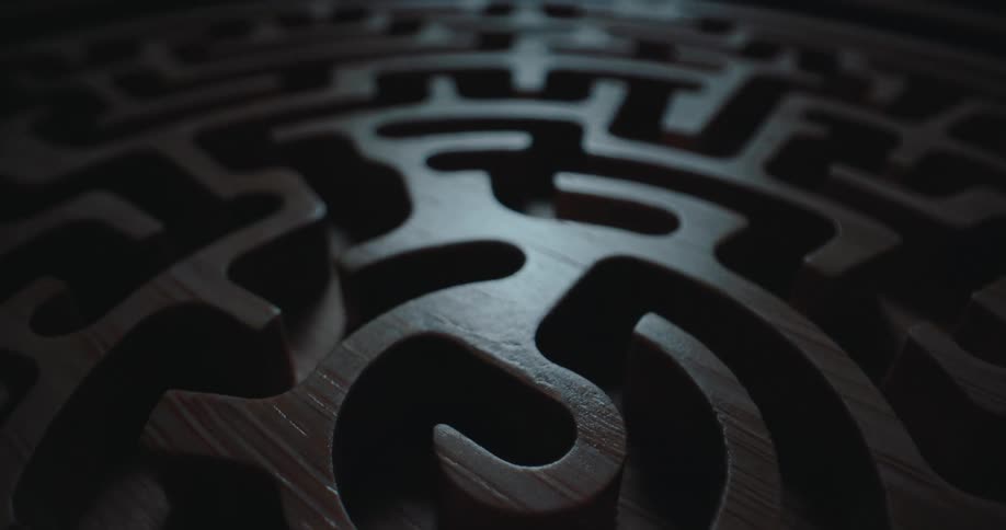 Circular wooden maze with a spiral pattern and low lighting
