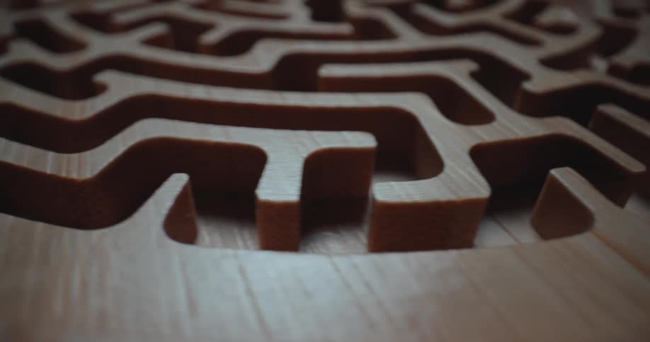 A close view of a carved wooden maze with intricate circular paths and smooth grain textures under soft light
