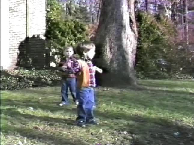 Children playing on a residential lawn in front of a house