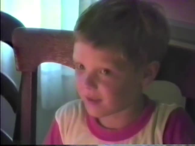 Kid smiles while blowing out candles at his birthday party
