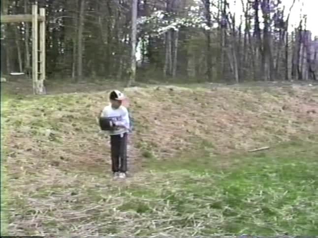 Two boys playing baseball on a grassy area near a house