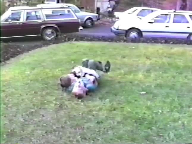 Two children are wrestling on the lawn