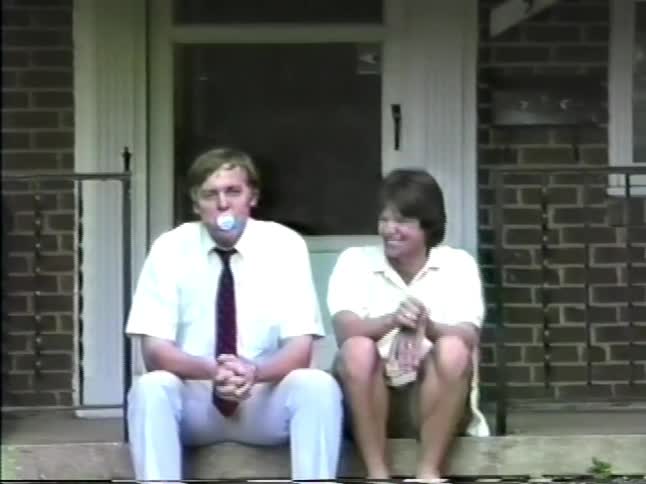 The man and woman sit on the steps and put a pacifiers in their mouth