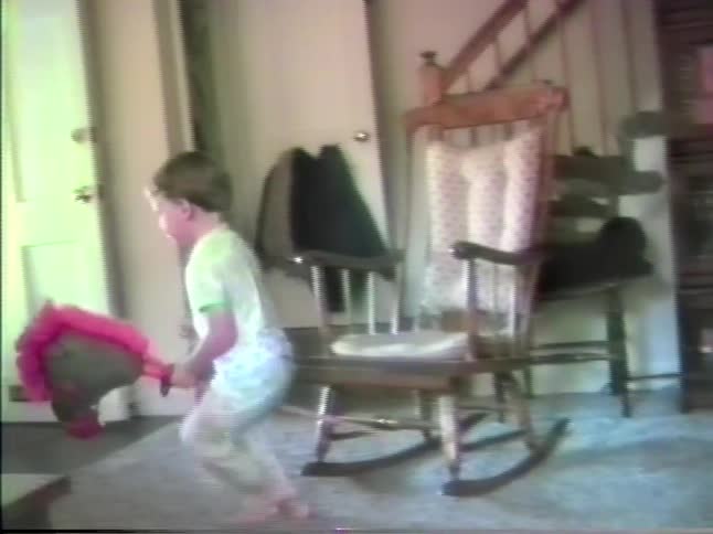 Child playing a musical instrument and another playing with a stick shaped like a toy horses head