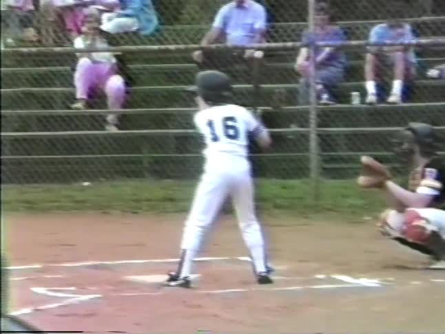 A young boy stands and takes a pitch while playing in a baseball game