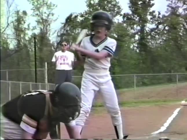Children playing baseball on a dirt field with a batter and catcher in position
