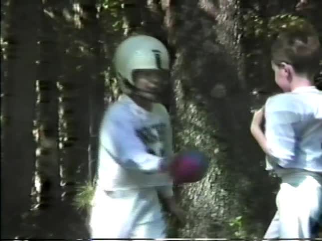 Children playing american football with a helmet and ball in a wooded area