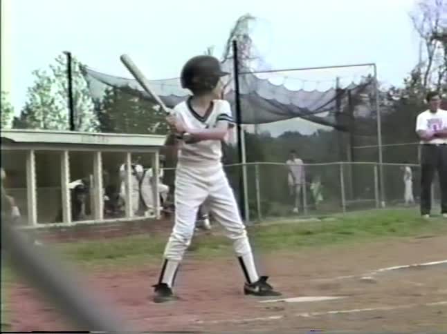 A boy swings a bat while playing in a baseball game
