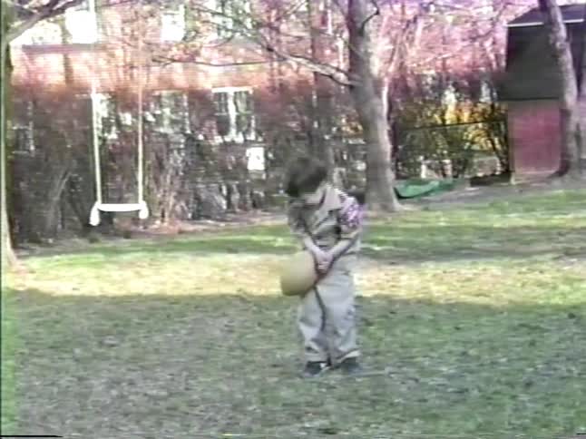 Adult guiding children during a baseball game on a residential lawn