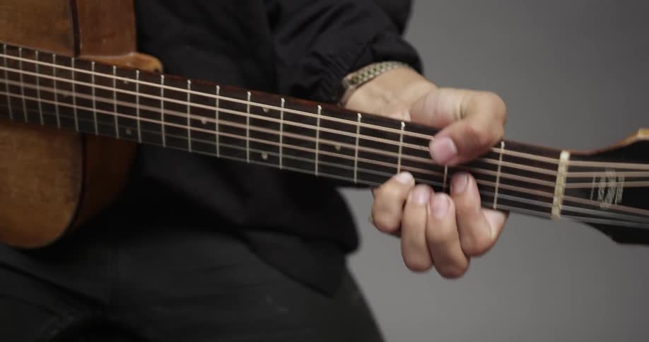 A person plays the guitar while sitting