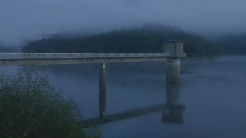Small building at the end of a pier over the water along the coast under a foggy sky
