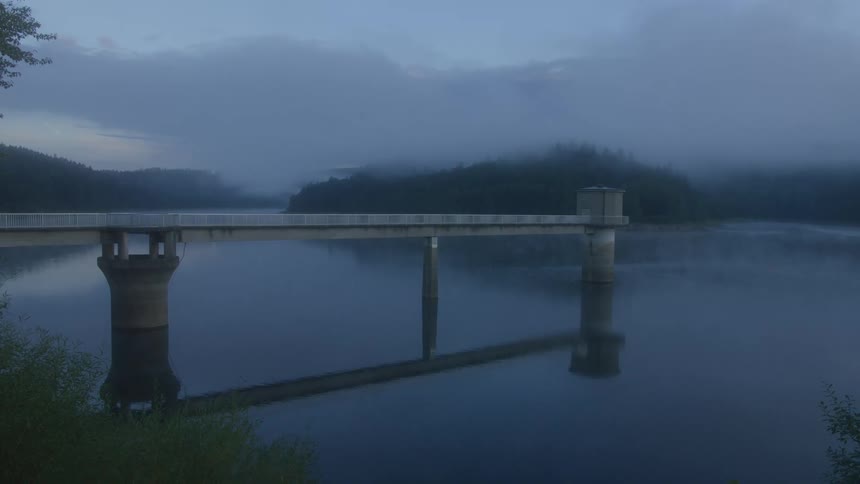 Water reflects the dock while light fog covers the area