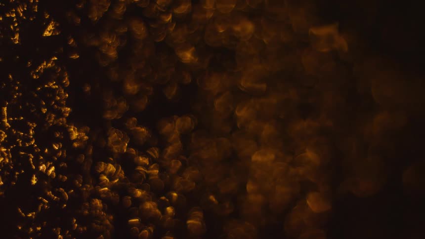 Abstract texture with scattered golden luminous particles on a dark background