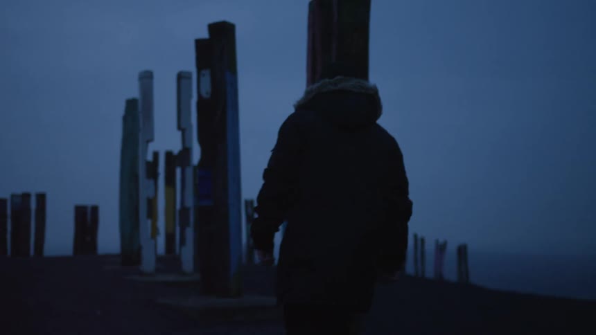 Hiker walks near posts at the edge of a mountain
