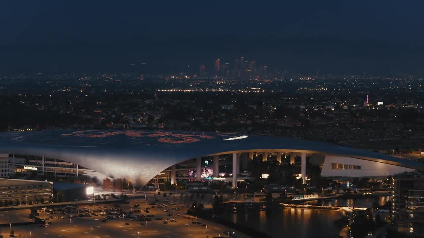 Illuminated stadium at night in an urban area with a city skyline in the background