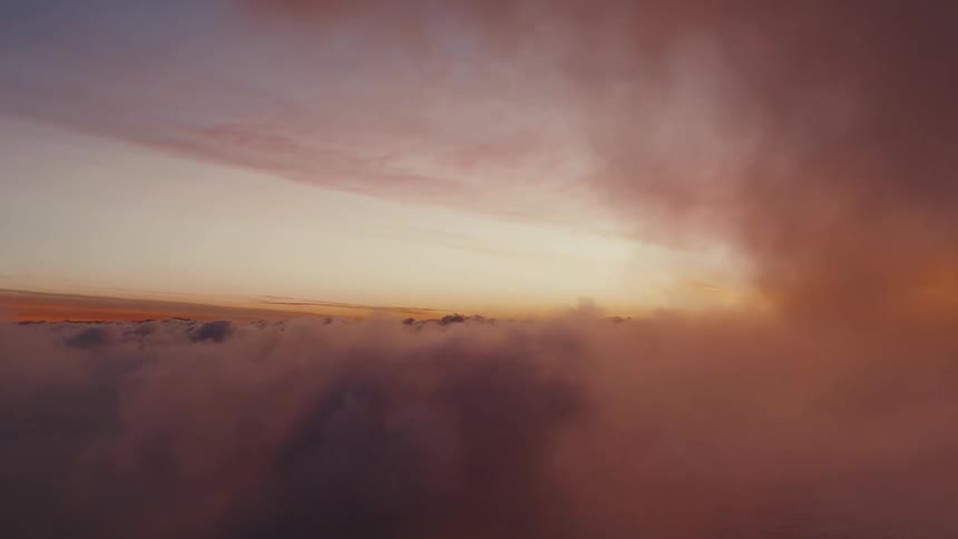 Sea of clouds under a dawn sky with golden light on the horizon